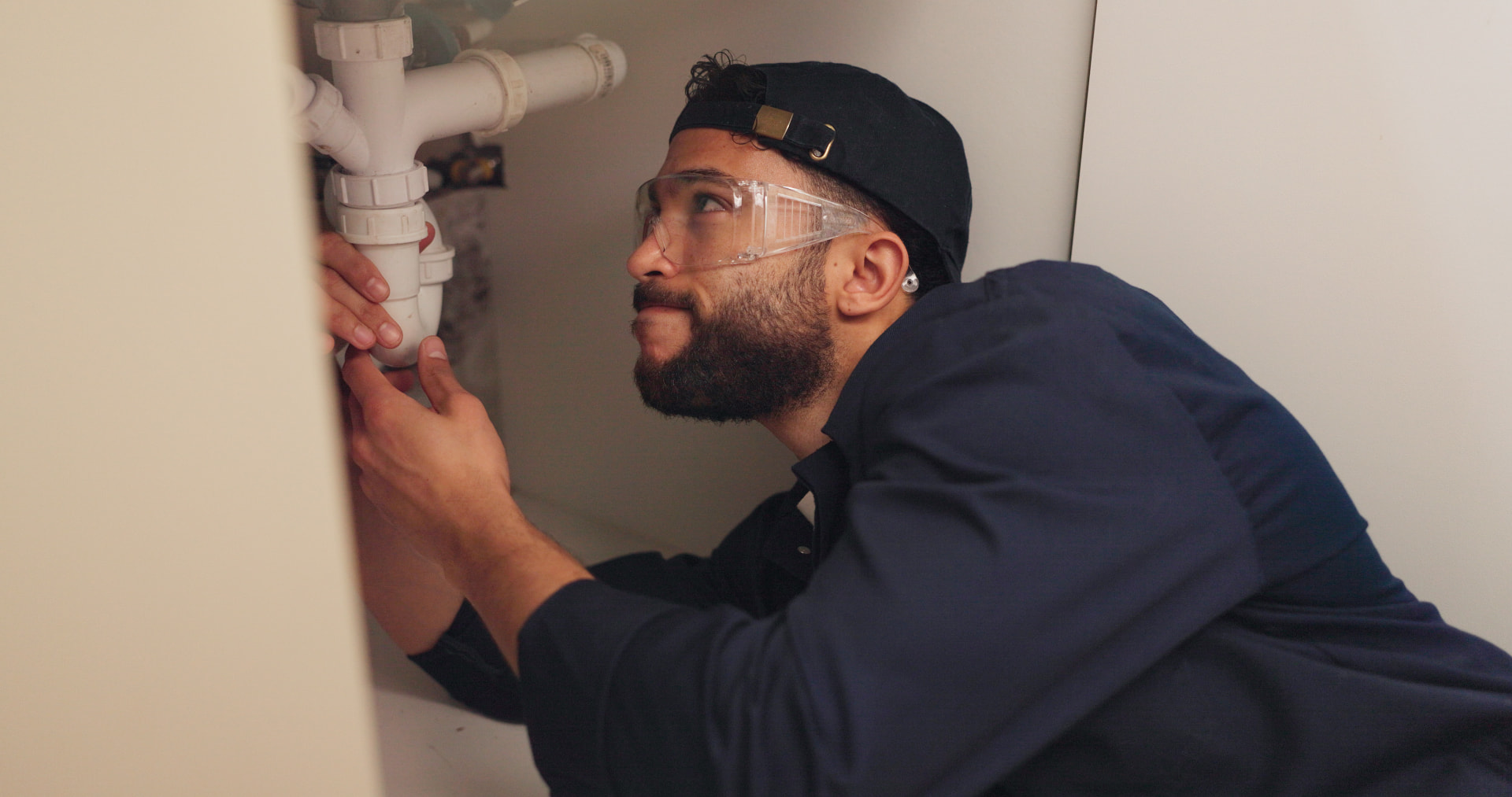 Plumber working on pipes beneath a sink during a renovation